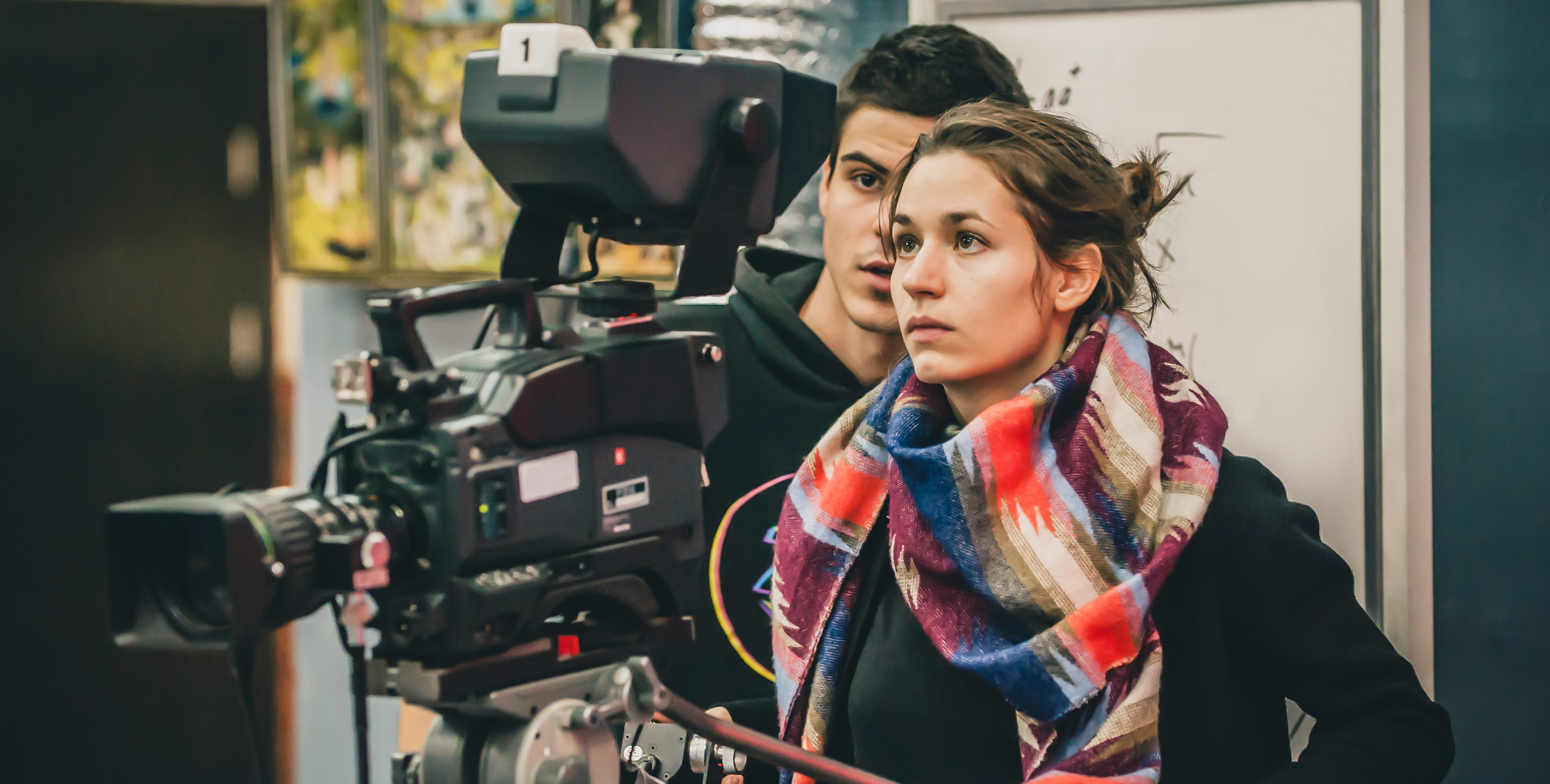 Cameraman standing behind female worker filming with camera