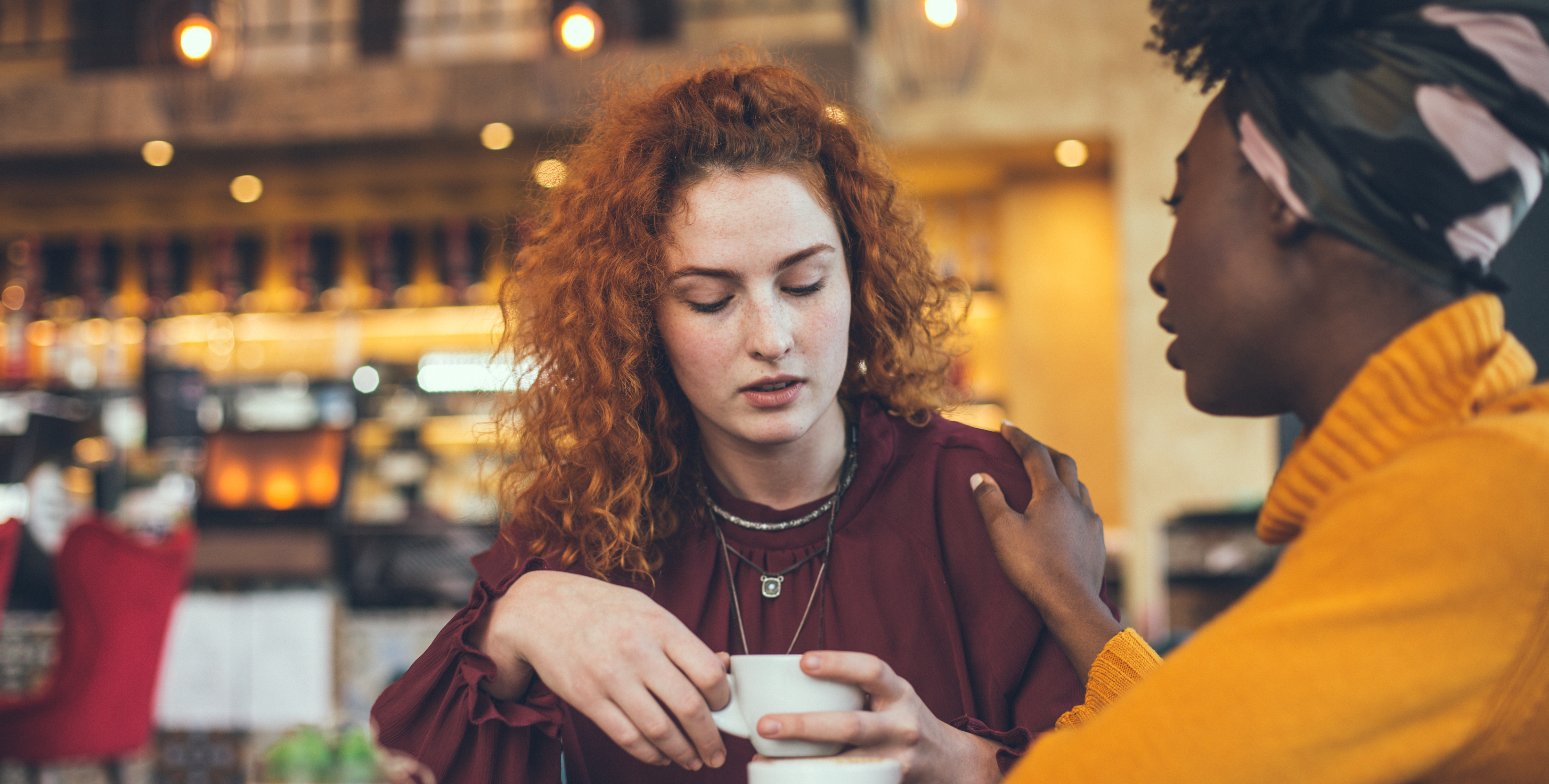 A young women talking to a friend and showing empathy in a cafe