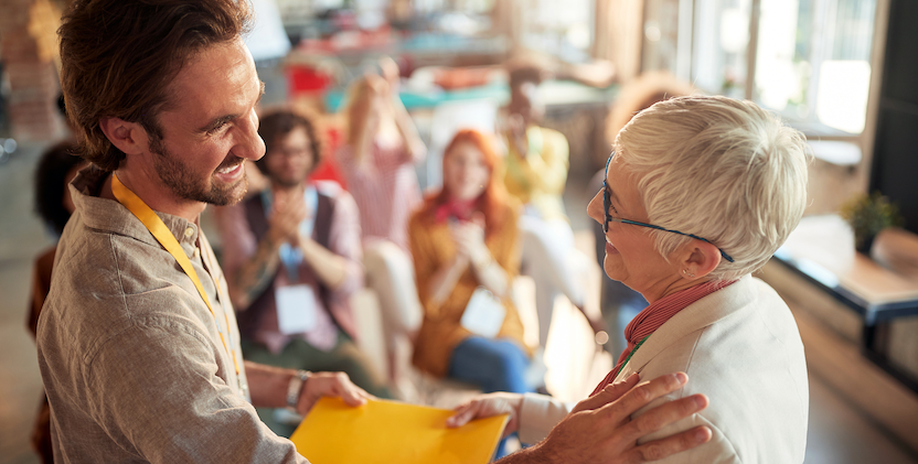 Elderly women being presented with gift at work celebration