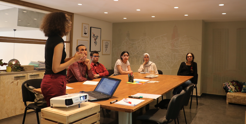 Group of people in room and one women presenting