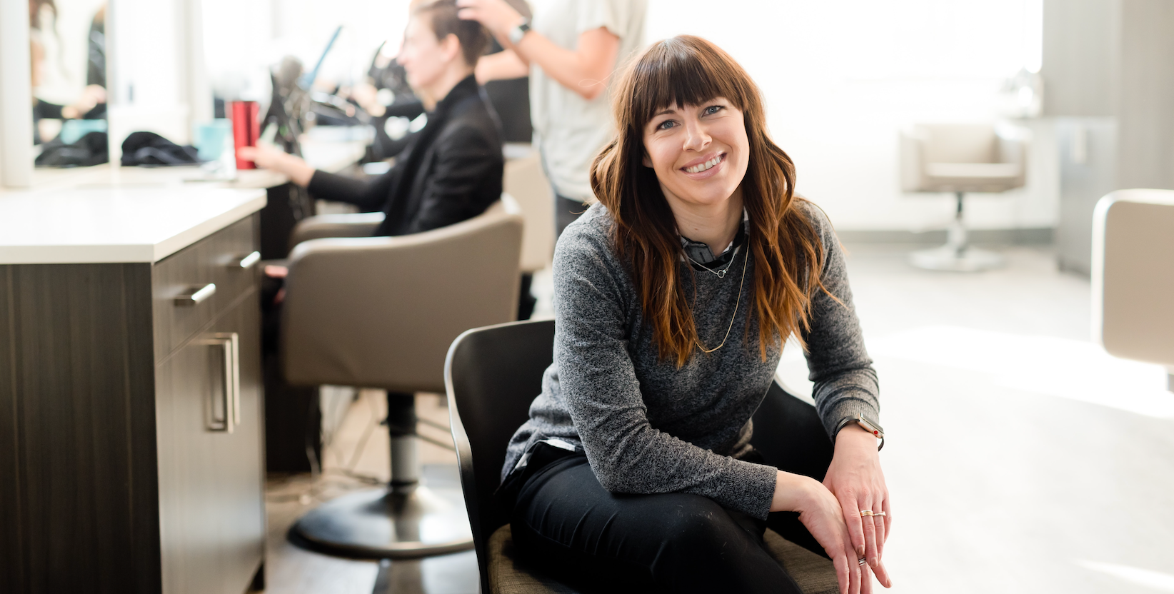 Women smiling into camera as a boos at hairdressing salon