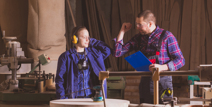 Young women and man touching elbows while working in workshop