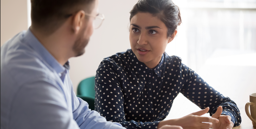 Indian women talking to co-worker at desk