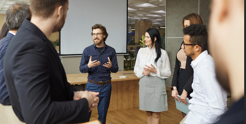 Man talking to colleagues standing up in meeting room
