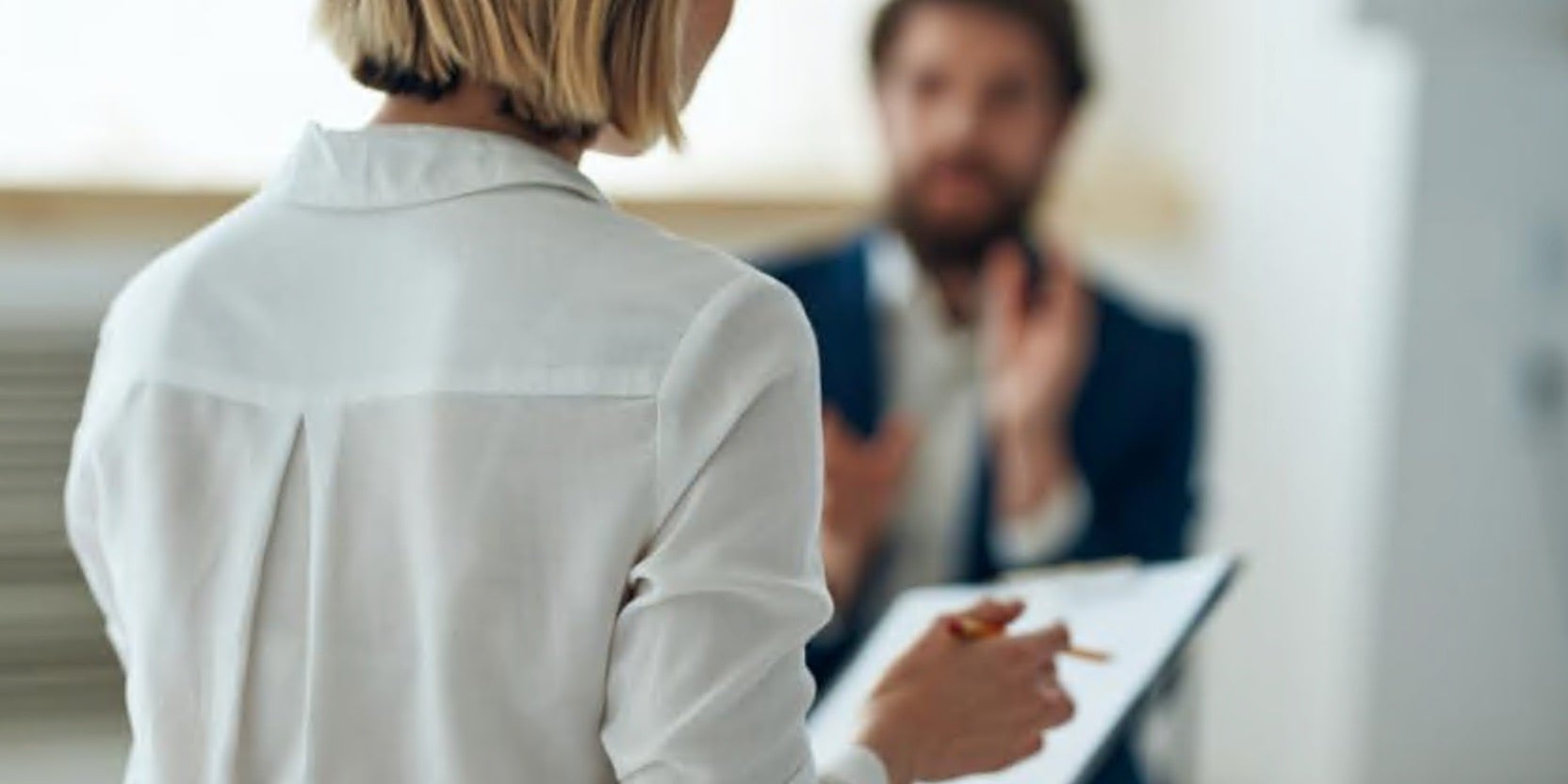 Women with clipboard standing in front of man talking