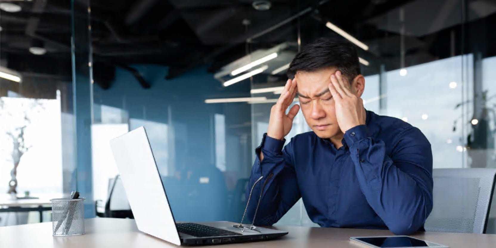 Man sitting at desk with head in hands