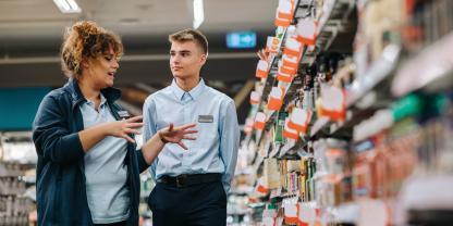 Image of female supervisor talking to young colleague in supermarket