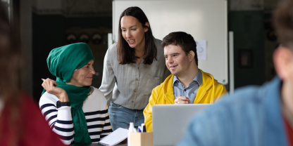 Image of three people in discussion over a laptop computer