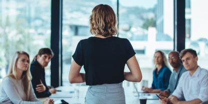 Image of women facing table of people talking during meeting