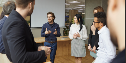 Man talking to colleagues standing up in meeting room