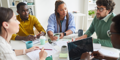 Group of people in room sitting at table in discussion