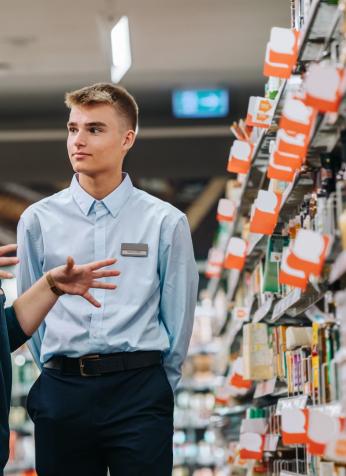 Image of female supervisor talking to young colleague in supermarket